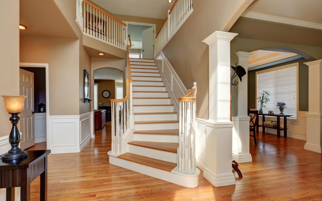 Sunny hallway interior with a staircase and hardwood floor.